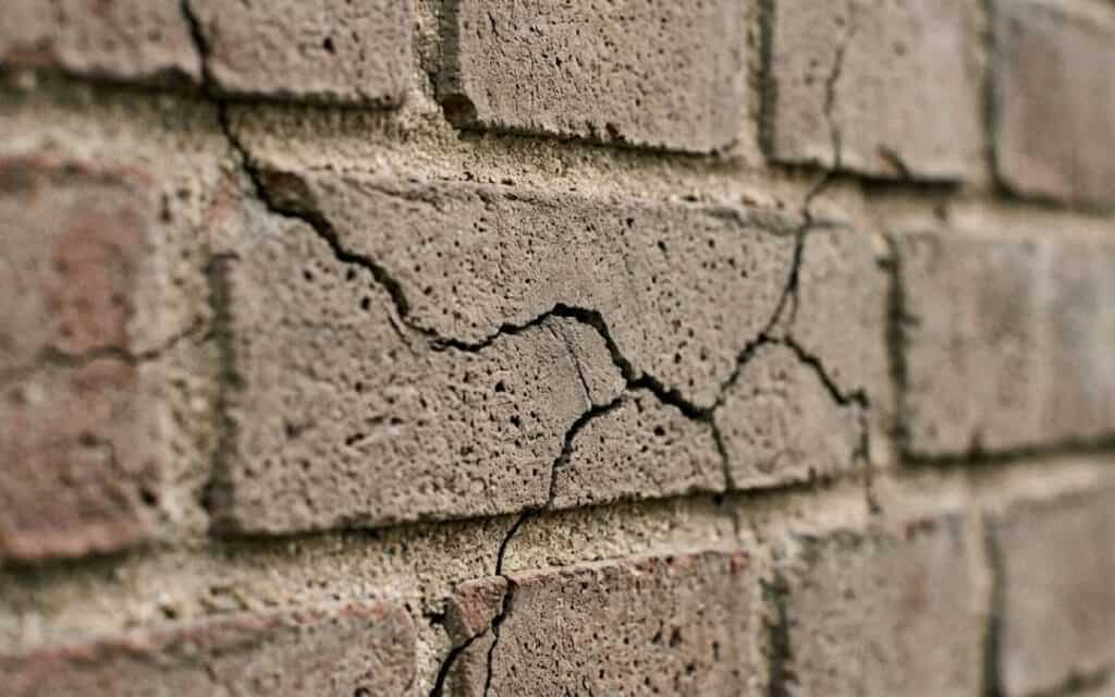 small-things-big-arguments-cracked-wall Close-up of a cracked brick wall with several small cracks spreading across the surface